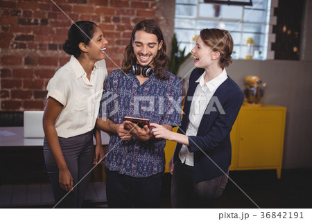 Cheerful young friends standing with digital tablet Cheerful young friends standing with digital tablet 36842191