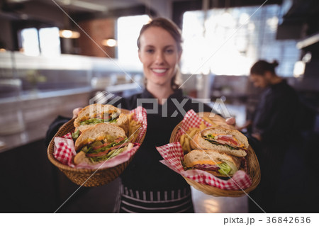 Portrait of smiling young waitress serving fresh burgers at coffee shop Portrait of smiling young waitress serving fresh burgers at coffee shop 36842636