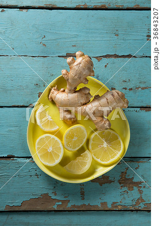 Lemon slices and ginger in yellow plate on table 36843207