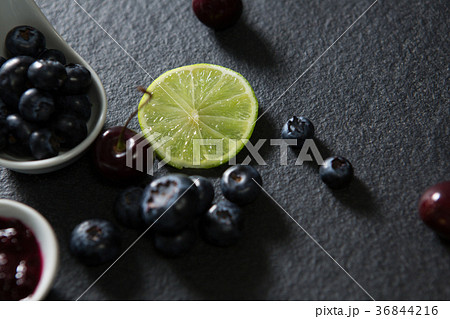 Slice of lemon and spoon with blueberries on black background 36844216