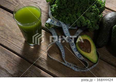 Mustard greens, avocado, measuring tape and juice on wooden table 36844424