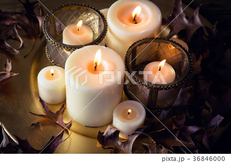Lit candles and dry leaves on table 36846000