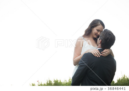 Bridegroom lifting bride while standing against clear sky in park Bridegroom lifting bride while standing against clear sky in park 36846441