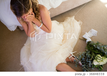 High angle view of bride in wedding dress crying while sitting by bed 36846559