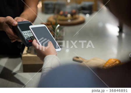 Woman paying bill through smartphone using NFC technology Woman paying bill through smartphone using NFC technology 36846891