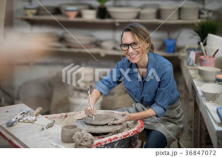 Portrait of female potter molding plate with hand tool 36847072