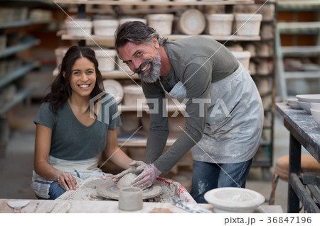 Portrait of male potter assisting female potter 36847196