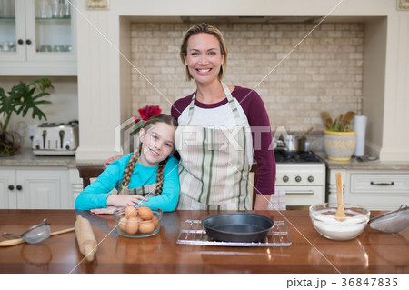 Smiling mother and daughter standing in the kitchen 36847835