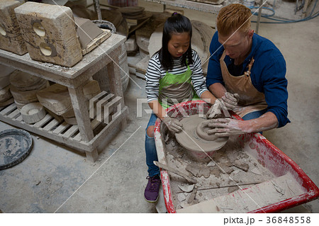 Male potter assisting girl in molding a clay Male potter assisting girl in molding a clay 36848558
