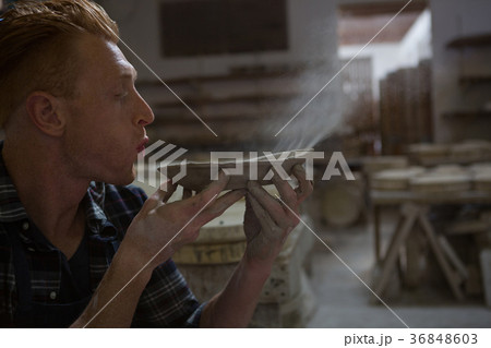 Male potter blowing dust from a bowl Male potter blowing dust from a bowl 36848603
