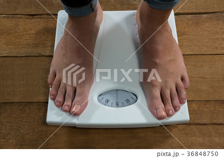 Woman checking her weight on a weighing machine Woman checking her weight on a weighing machine 36848750