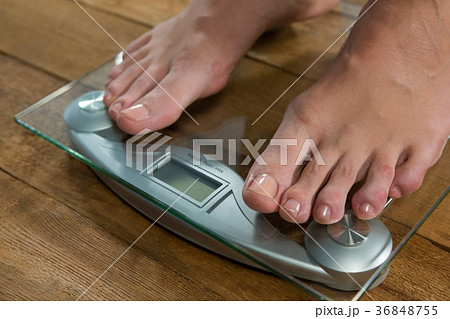 Woman checking her weight on a weighing machine 36848755