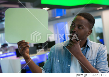Male executive holding speech bubble in office 36849129