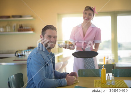 Waitress serving meal to man in restaurant 36849499