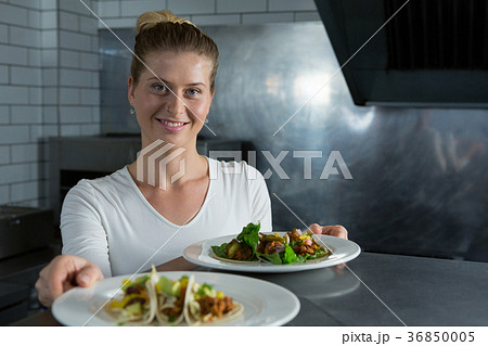 Female chef holding food plate Female chef holding food plate 36850005