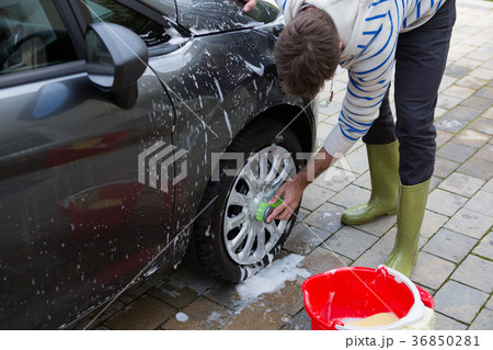Auto service staff washing a car tyre with sponge Auto service staff washing a car tyre with sponge 36850281