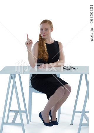Female executive pointing upwards while sitting at desk Female executive pointing upwards while sitting at desk 36850801