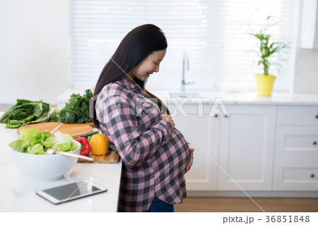Smiling pregnant woman touching her stomach Smiling pregnant woman touching her stomach 36851848