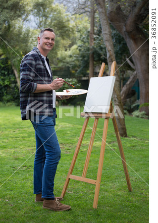 Man painting on canvas in garden Man painting on canvas in garden 36852091