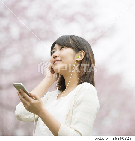 桜の前で音楽を聴く女性 36860825