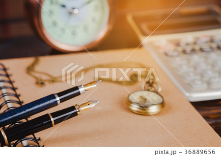 pocket watch over book note on wood table . 36889656