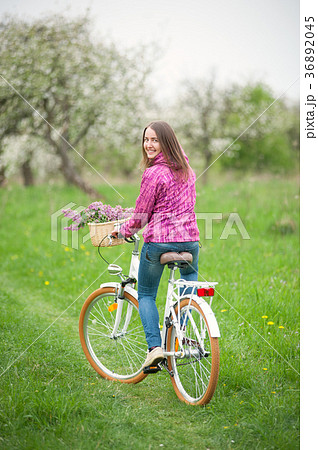 Female cyclist riding a vintage white bicycle in spring garden Female cyclist riding a vintage white bicycle in spring garden 36892045