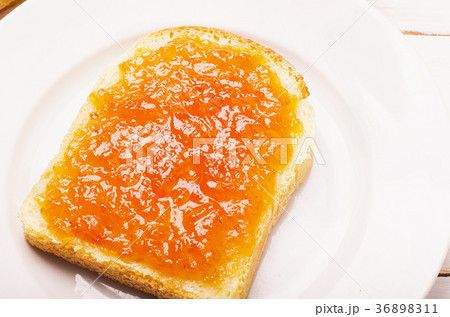 Bread with orange peach jam in a plate 36898311