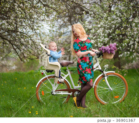 Blonde female with city bicycle with baby in bicycle chair 36901367