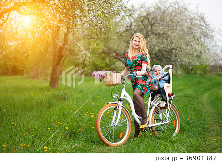 Blonde female riding city bicycle with baby in bicycle chair 36901387