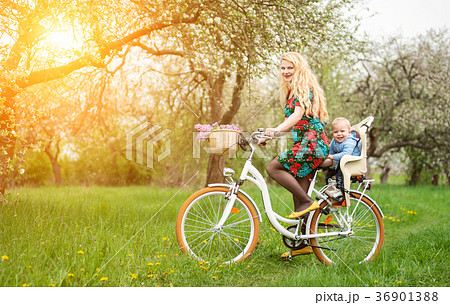 Blonde female riding city bicycle with baby in bicycle chair 36901388