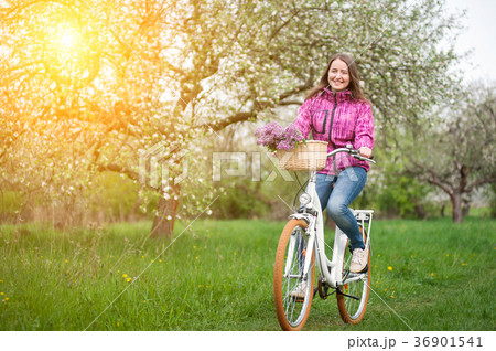 Female cyclist riding a vintage white bicycle in spring garden Female cyclist riding a vintage white bicycle in spring garden 36901541