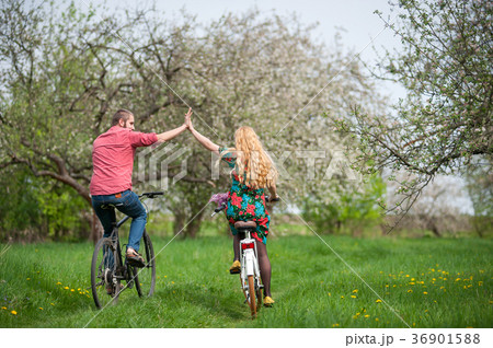 Loving young couple riding bicycles in the spring garden Loving young couple riding bicycles in the spring garden 36901588