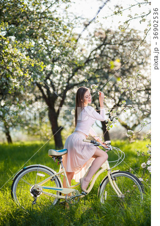 Beautiful female cyclist with retro bicycle in the spring garden 36902536