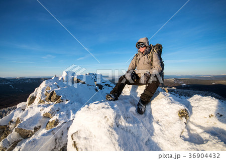 Hiker with backpack sitting and having rest on the 36904432