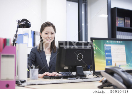 会社のパソコンで仕事をする若い女性社員、カメラ目線 会社のパソコンで仕事をする若い女性社員、カメラ目線 36910413