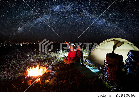 Couple enjoying near campfire and tent at night 36910666