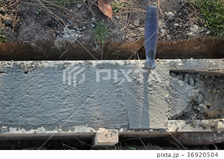 Trowel at wall foundation, concrete in formwork and tool 36920504