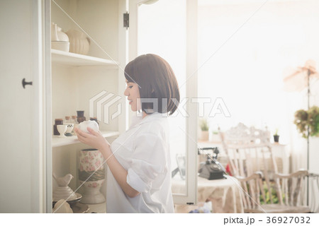 girl choosing ceramic cup in a white cupboard 36927032