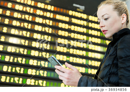 Woman at airport in front of flight information 36934856