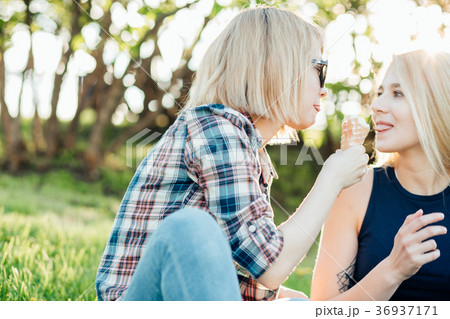 two young woman eating ice cream cones on hot two young woman eating ice cream cones on hot 36937171