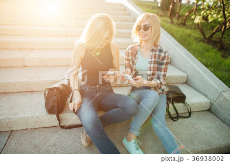 Two friends looking at pictures on a cellphone 36938002