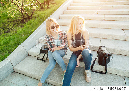 Two friends looking at pictures on a cellphone 36938007