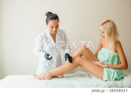 Beautician waxing woman a leg at salon. Depilation 36938037