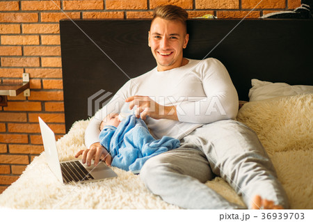 man feeding little baby while lying on bed and man feeding little baby while lying on bed and 36939703