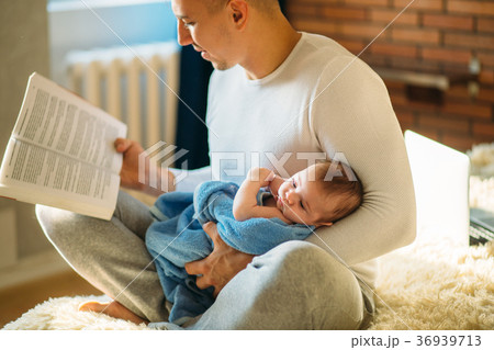 Young father and reading book to little baby 36939713