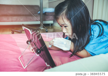 Cute asian child using tablet with iv drip on hand 36945575