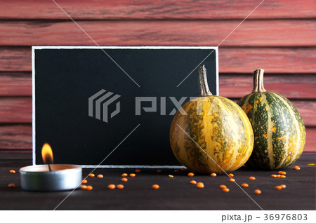 Black board, pumpkin and candle on brown 36976803