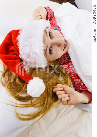 Happy woman wearing pajamas and Santa Claus hat Happy woman wearing pajamas and Santa Claus hat 36980455