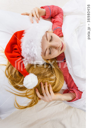 Happy woman wearing pajamas and Santa Claus hat Happy woman wearing pajamas and Santa Claus hat 36980456