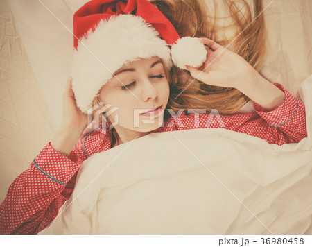 Happy woman wearing pajamas and Santa Claus hat Happy woman wearing pajamas and Santa Claus hat 36980458